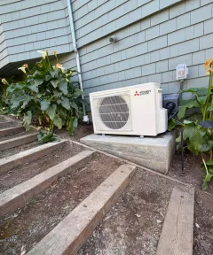 Mitsubishi outdoor unit beside a garden and steps