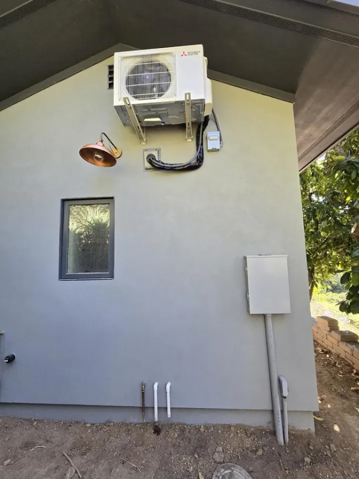 Wall-mounted outdoor unit with lines routed down an exterior wall