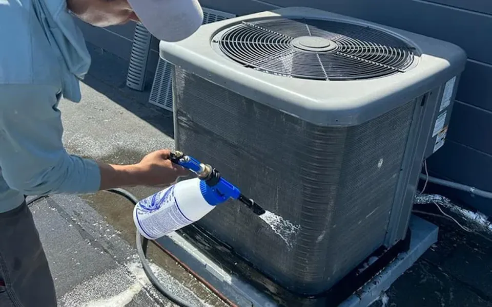 Technician cleaning an outdoor air conditioning unit