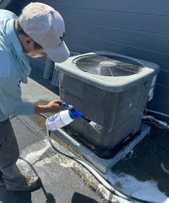 Technician cleaning an outdoor air conditioning unit