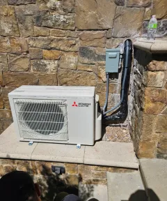 Ductless outdoor unit mounted on a stone wall