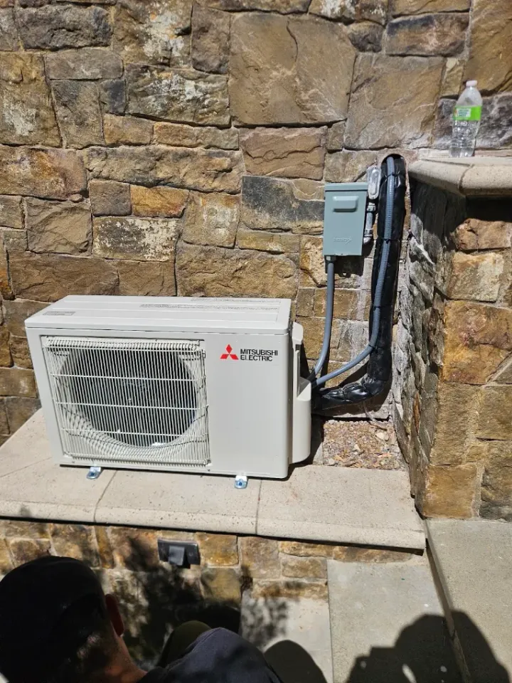 Compact outdoor unit mounted beside a stone wall