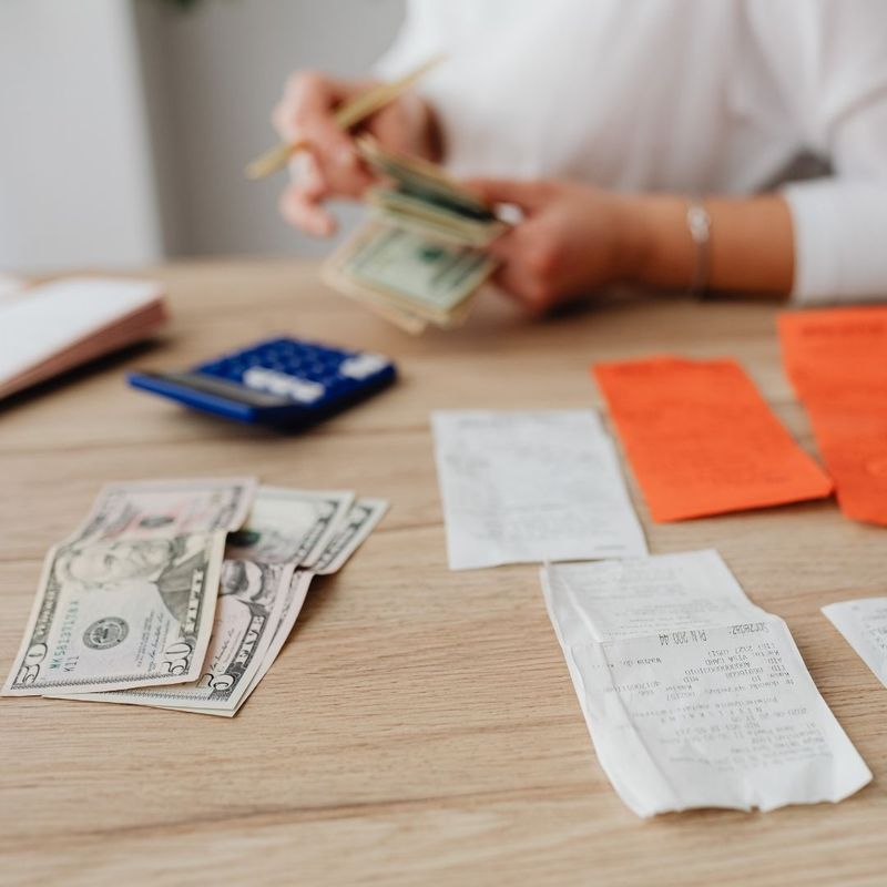 Hands counting cash beside a calculator and bills